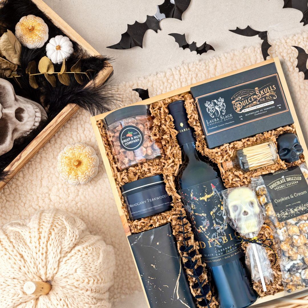 Gourmet gift set with wine, snacks, and decorative items on a textured surface with fall vibes. 