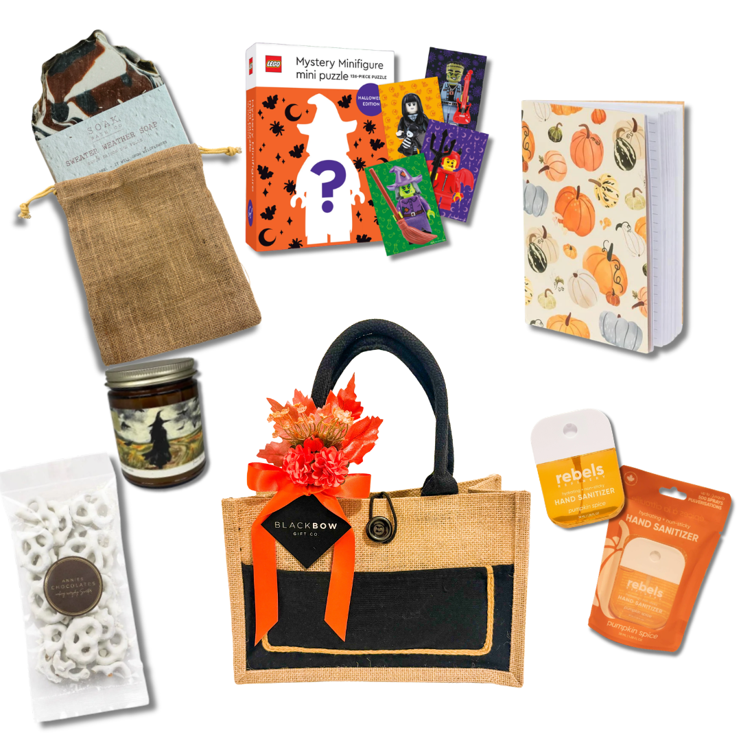 A Touch of Fall gift basket with a pumpkin journal, seasonal candle, LEGO mystery puzzle, sweater weather soap and sweet treats in a reusable tote by Black Bow Gift Co.