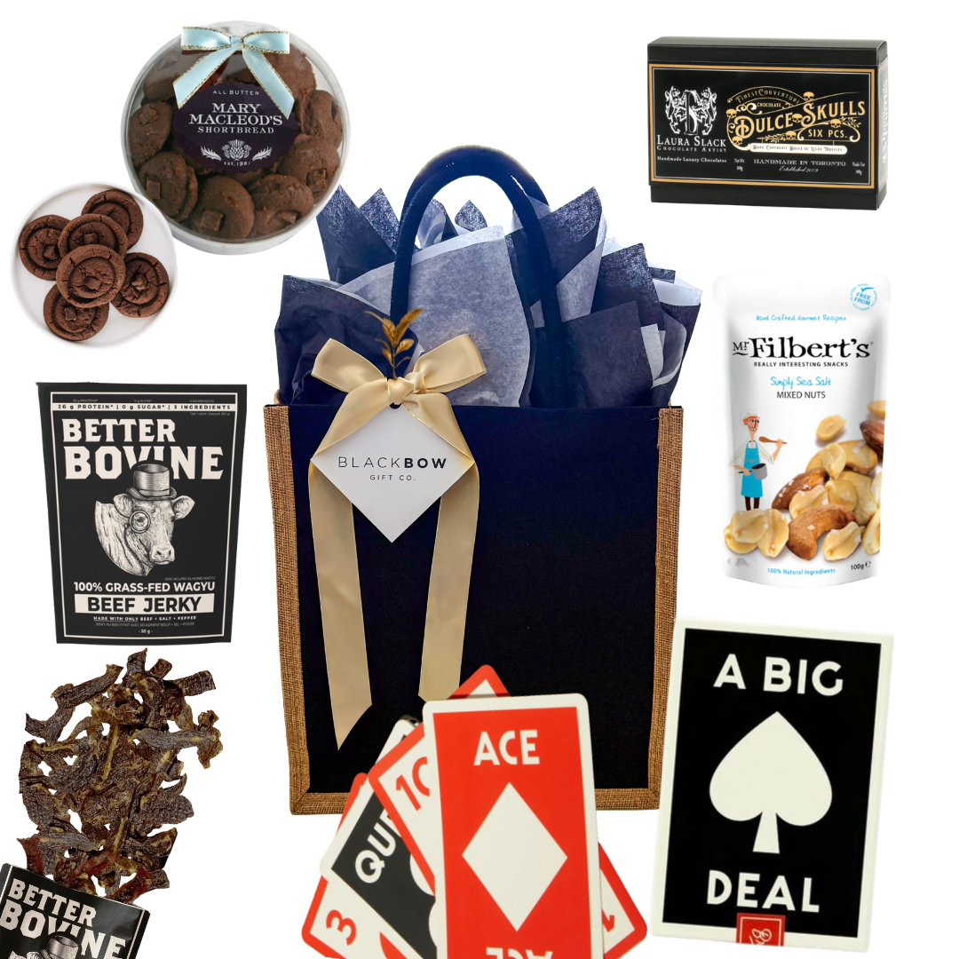 Shareable snack gift with oversized playing cards, chocolates, nuts, jerky, and hot chocolate, packaged in a black fabric tote.