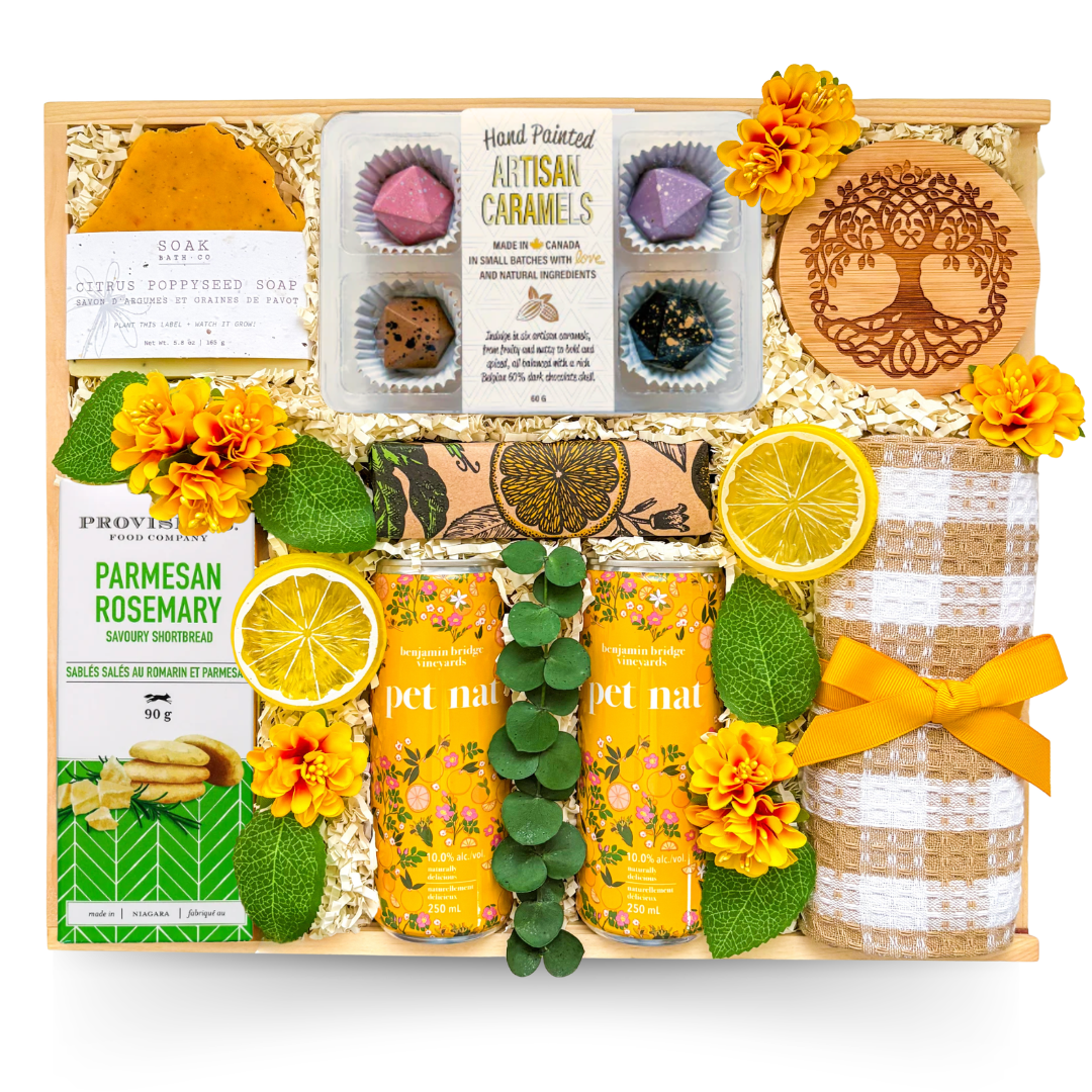 Wooden gift box featuring sparkling botanical beverages, gourmet cookies, artisan caramels, handcrafted soap, decorative coaster, tea towel, and thoughtful gourmet treats in cheerful yellow accents.