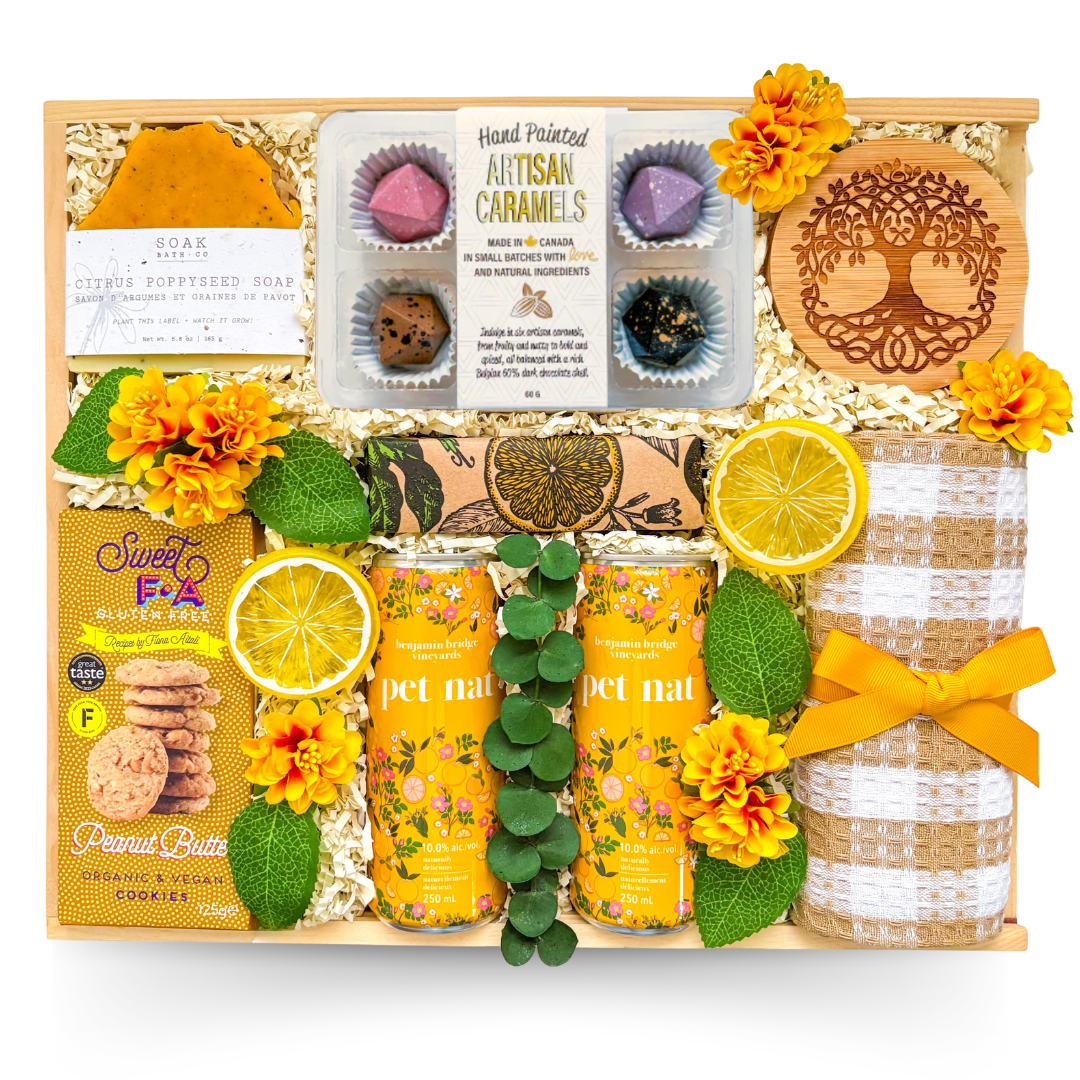Wooden gift box featuring sparkling botanical beverages, gourmet cookies, artisan caramels, handcrafted soap, decorative coaster, tea towel, and thoughtful gourmet treats in cheerful yellow accents.