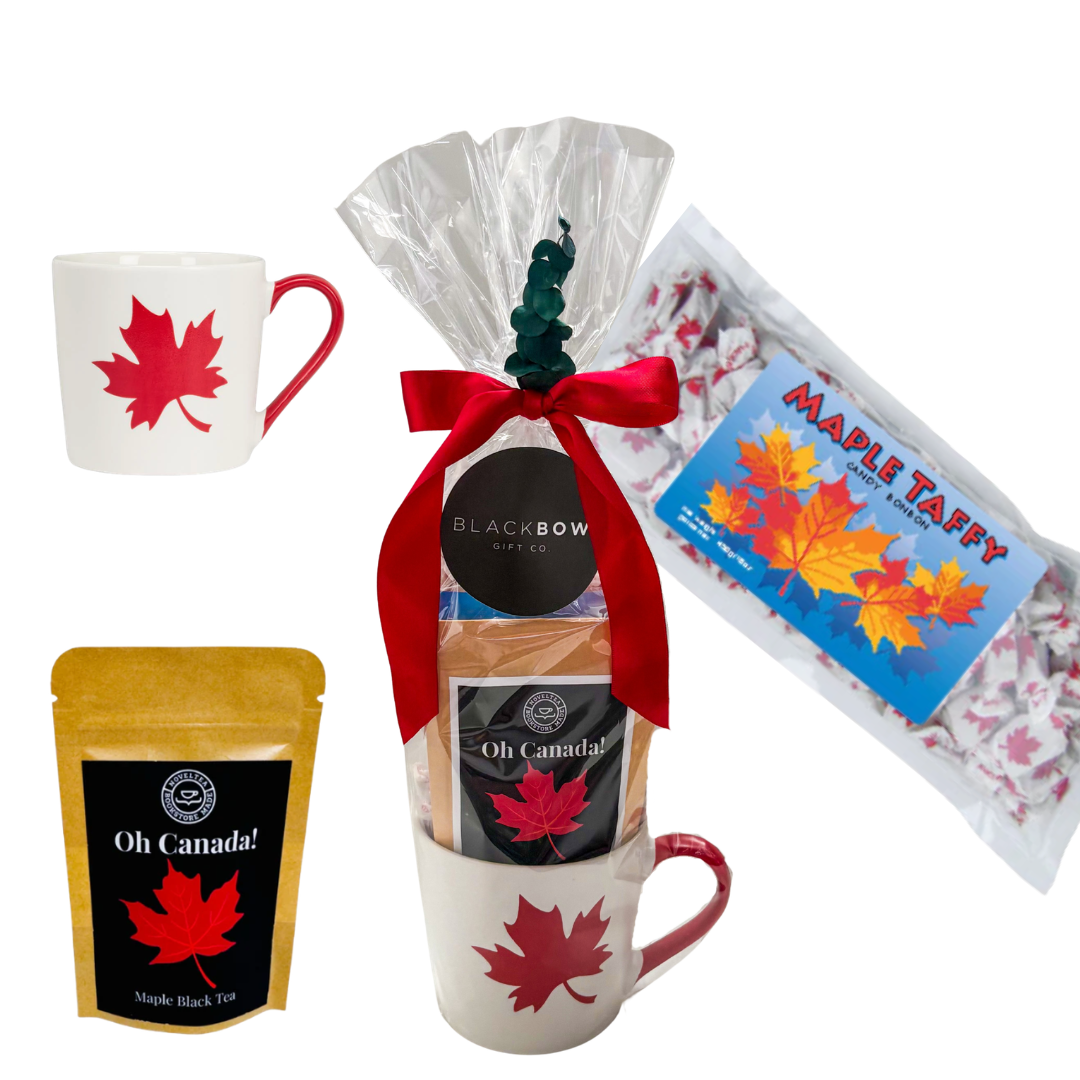 Canadian-themed gift featuring a maple leaf mug, maple treats, and Canadian-inspired snacks presented in a cello bag with ribbon and decorative accents by Black Bow Gift Co.