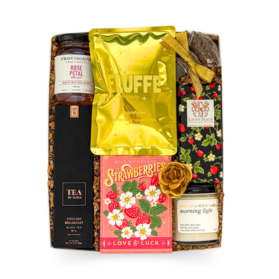 Luxury celebration gift box with English breakfast tea, champagne cotton candy, rose petal jam, diamond bottle stopper, candle, and gourmet treats in gold-accented packaging