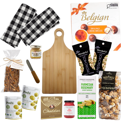Woven picnic gift basket featuring a bamboo serving board, tea towels, gourmet snacks, olives, pistachios, popcorn, chocolates, and entertaining essentials by Black Bow Gift Co.