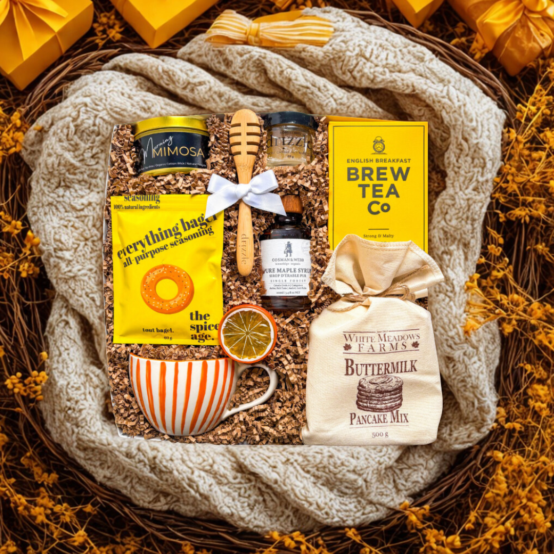 Gift basket with tea, pancake mix, and other items on a textured surface.