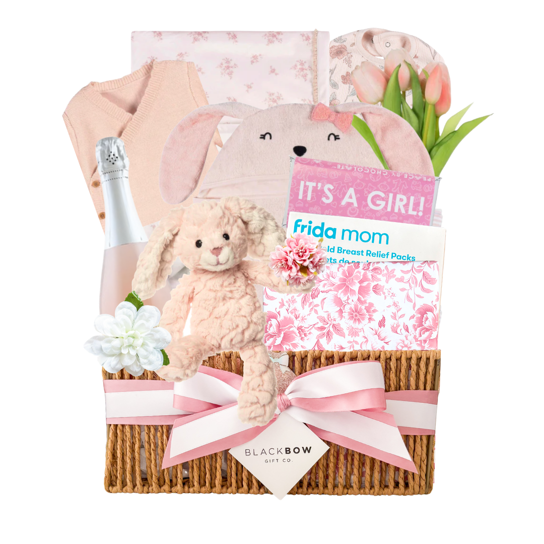 Blush Beginnings baby girl gift basket featuring soft pink baby essentials, plush bunny, celebration bottle, keepsake items, and elevated baby gifting by Black Bow Gift Co.
