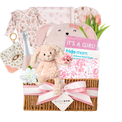 Blush Beginnings baby girl gift basket featuring soft pink baby essentials, plush bunny, celebration bottle, keepsake items, and elevated baby gifting by Black Bow Gift Co.
