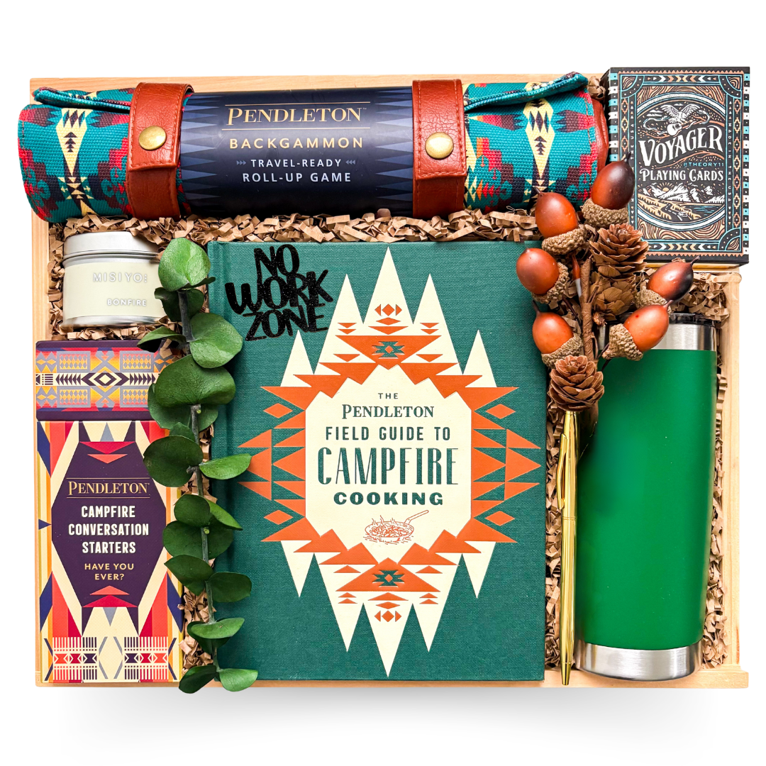 Luxury campfire-themed gift box with Pendleton campfire cooking book, backgammon set, gourmet treats, travel tumbler, candle, and games in wooden keepsake box.
