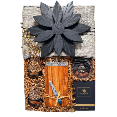 Luxury couple gift with blanket, candle, wine glasses, Nova Scotia-themed board, cheese knife, and chocolate treats, styled for cozy, sensory coastal indulgence.