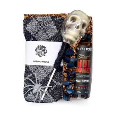 Cozy With a Kick fall gift box featuring a charcoal knit throw blanket, locally made Halifax hot honey and white chocolate skull, thoughtfully packaged by Black Bow Gift Co.