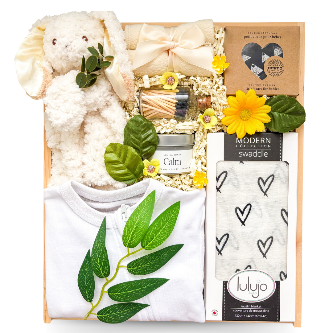Wooden baby gift box featuring a soft plush lamb, swaddle blanket, baby sleeper, cozy socks, soy candle, heart-shaped soap, decorative matches, and nursery keepsakes for welcoming a new baby.
