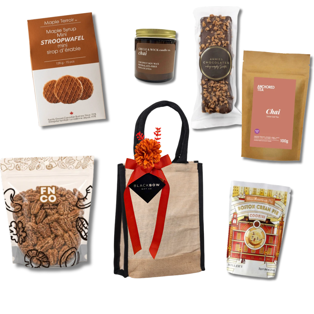 Enjoy gourmet gift basket with tea, cookies, maple stroopwafels, maple cinnamon pecans, chocolate and a cozy candle presented in a reusable tote by Black Bow Gift Co.