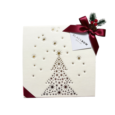Elegant white Christmas gift box decorated with a gold star Christmas tree design, burgundy ribbon, and festive greenery.