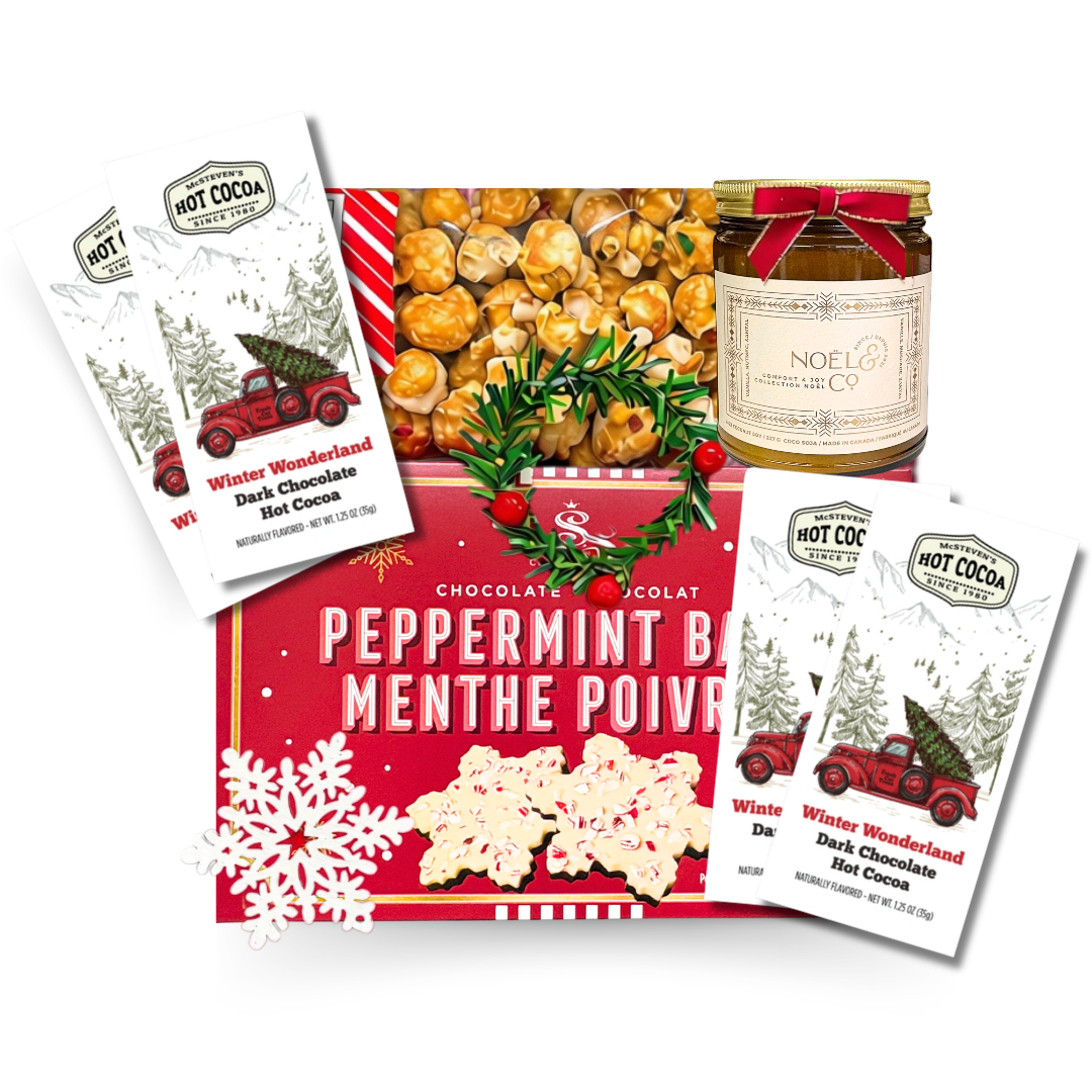 Festive Christmas gift basket featuring peppermint bark, caramel popcorn, winter-themed dark chocolate hot cocoa packets, and a holiday-scented candle.