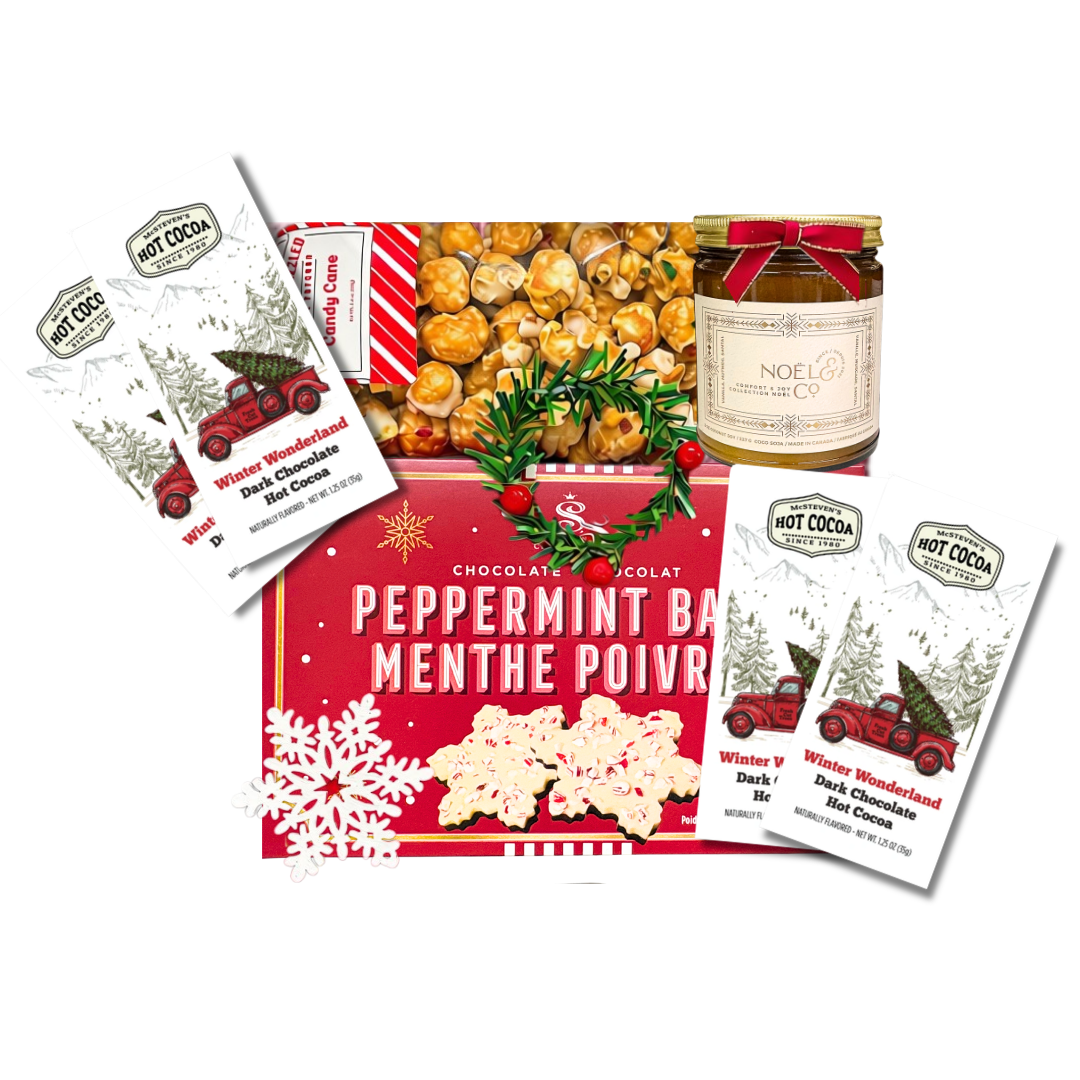Festive Christmas gift basket featuring peppermint bark, caramel popcorn, winter-themed dark chocolate hot cocoa packets, and a holiday-scented candle.