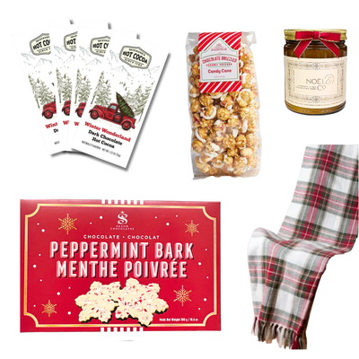 Festive Christmas gift basket featuring peppermint bark, caramel popcorn, winter-themed dark chocolate hot cocoa packets, and a holiday-scented candle.