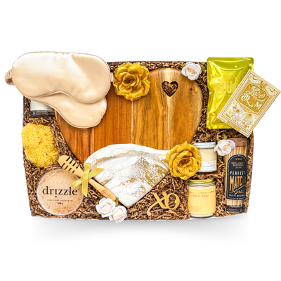 XL luxury keepsake gift box featuring a heart-shaped serving board, resin heart dish, silk sleep masks, bubble bath, candle, honey, sponge, bottle opener, safety matches, gourmet treats, olives, crackers, and charcuterie favourites.
