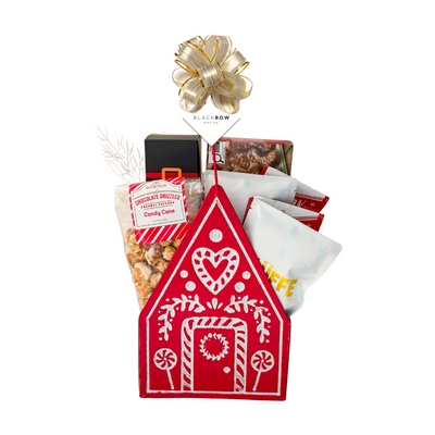 Holiday Happiness Christmas gift basket featuring a red gingerbread house keepsake filled with festive chocolates, cookies, candy cane popcorn and holiday treats.