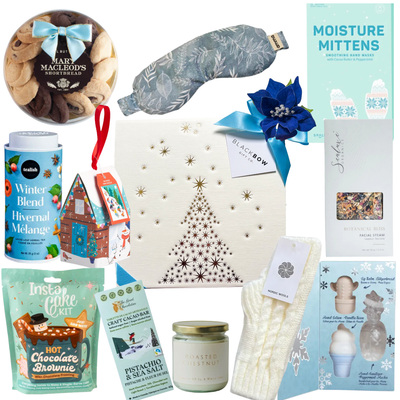 Holiday Essentials Box with cozy gloves, self-care items, roasted chestnut candle, festive treats, and a wrapped ornament in a gold-foil holiday box