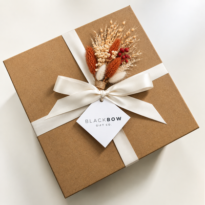 Exterior of Gift box, kraft coloured with Ivory Ribbon tied in a bow and has a orange with white fall accent in the centre of the bow.