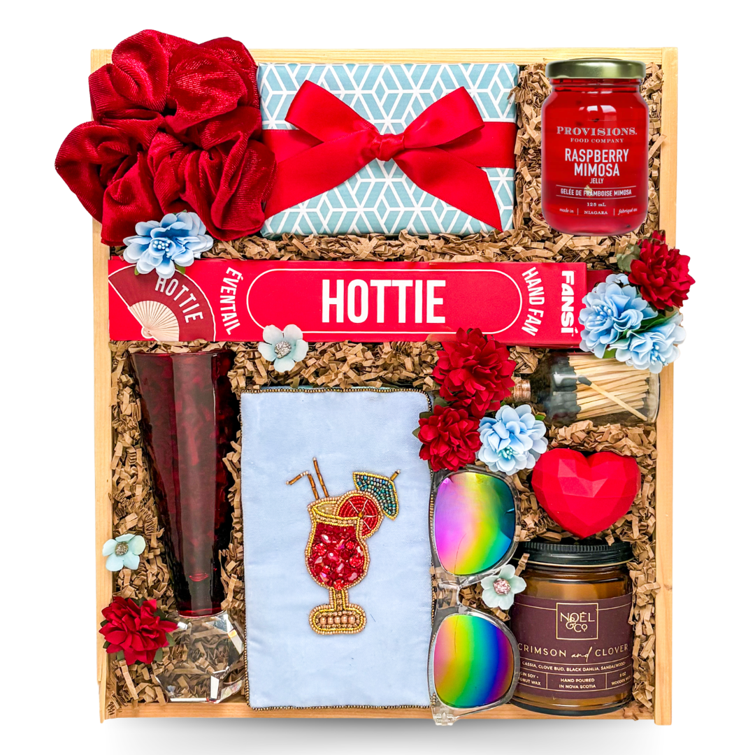 Luxury wooden keepsake gift box featuring colourful ribbons, sunglasses, beaded cocktail-themed glasses case, raspberry mimosa preserve with edible gold flakes, hand fan, candle, lip balm, gourmet chocolates, and celebration-inspired gifts.

