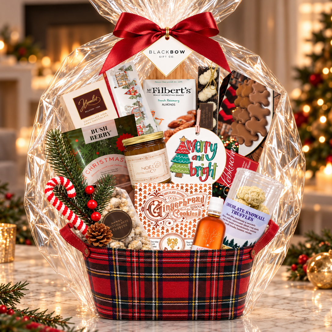 
Luxury Christmas gift basket in a red plaid container filled with gourmet chocolates, gingerbread cookies, nuts, festive treats and holiday keepsakes, wrapped in cellophane with a burgundy bow.