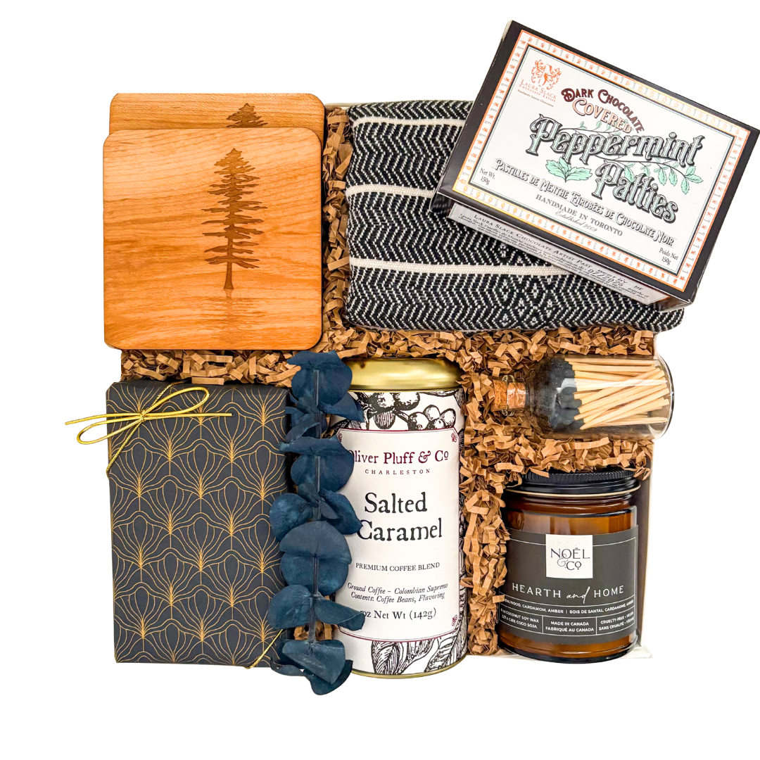 Luxury housewarming gift basket with premium gourmet foods, artisan coffee, handcrafted serving board, decorative tea towel, soy candle, soft throw, and premium home essentials in a luxury magnetic gift box.


