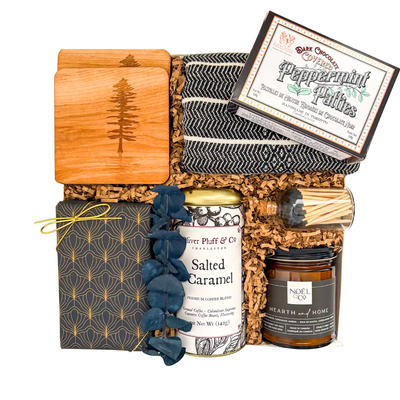 Luxury housewarming gift basket with premium gourmet foods, artisan coffee, handcrafted serving board, decorative tea towel, soy candle, soft throw, and premium home essentials in a luxury magnetic gift box.
