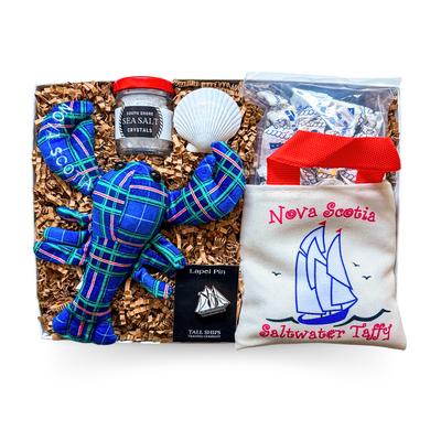 Nova Scotia Gift Box with Bluenose pin, tartan lobster, sea salt, and taffy in a sailboat bag styled as a coastal keepsake.