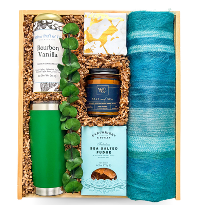 Cozy self-care gift with tumbler, candle, coffee, sweet treats, and soft scarf, styled for slow mornings and playful indulgence.