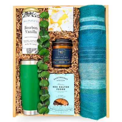 Cozy self-care gift with tumbler, candle, coffee, sweet treats, and soft scarf, styled for slow mornings and playful indulgence.