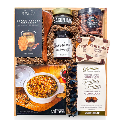 A premium wooden gift box tied with a grosgrain ribbon and accented with dried florals, filled with gourmet entertaining items including brie-themed accompaniments, crackers, spreads, nuts, cocktail mixers, chocolate truffles, and a white ceramic brie baker—styled for an elevated, shareable entertaining experience.