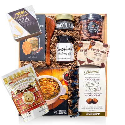 A premium wooden gift box tied with a grosgrain ribbon and accented with dried florals, filled with gourmet entertaining items including brie-themed accompaniments, crackers, spreads, nuts, cocktail mixers, chocolate truffles, and a white ceramic brie baker—styled for an elevated, shareable entertaining experience.