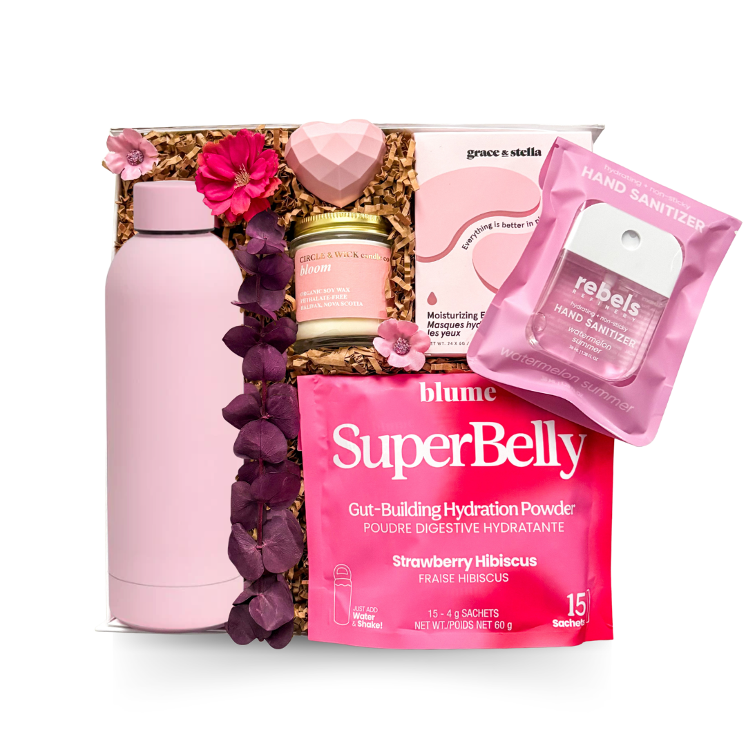 Luxury keepsake wellness gift box featuring a pink insulated bottle, hydrating eye masks, botanical candle, hydration powder, heart-shaped bath bomb, and premium self-care essentials in pink tones.

