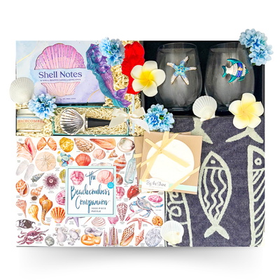 Luxury coastal gift basket in a large high-gloss black magnetic keepsake gift box featuring artisan coffee, breakfast favourites, gourmet treats, beach-themed stemless wine glasses, cozy throw, coastal stationery, puzzles, and premium seaside-inspired keepsakes.