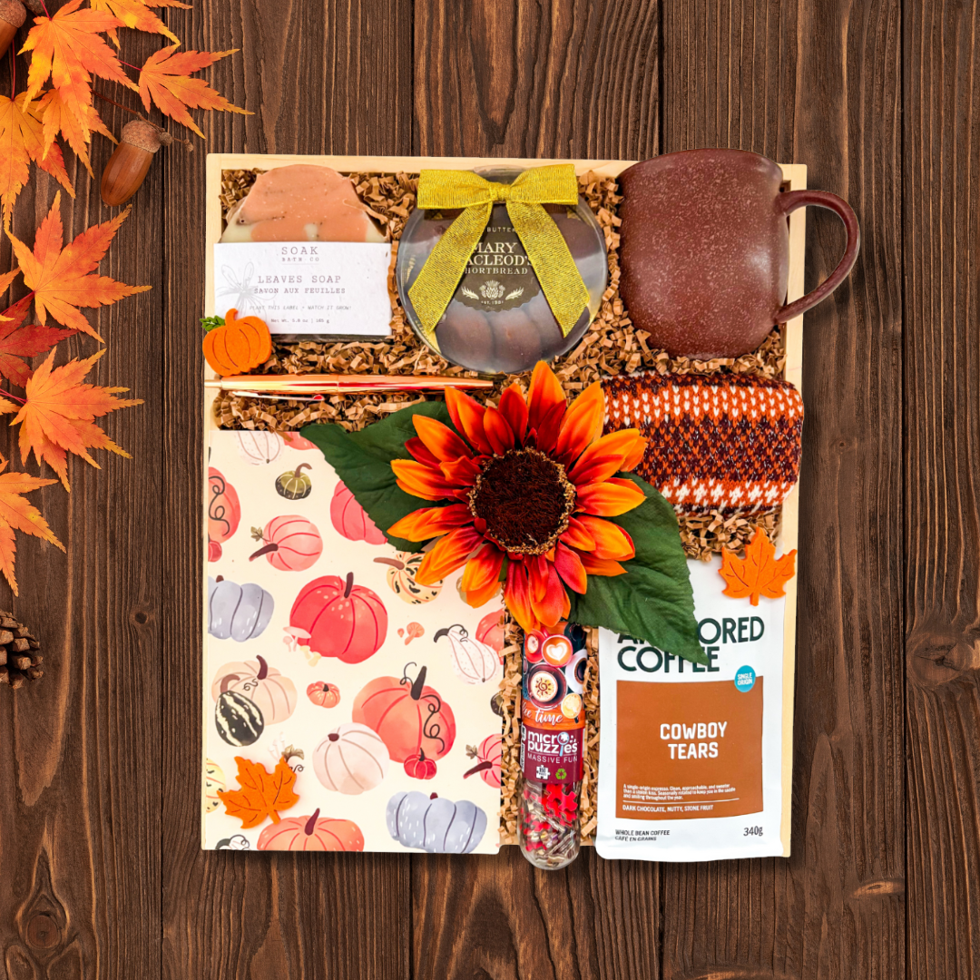 Gift set with coffee, sunflower, and decorative items on a wooden surface.Fall gift collection promotion feature with cozy socks, pumpkin notebook, mug, premium coffee, coffee puzzle and cookies and fall leaves all natural soap bar available for local gift delivery across Canada.