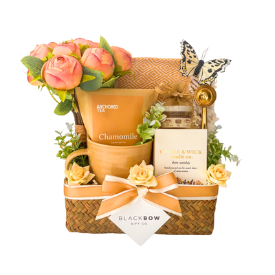Seagrass relaxation gift basket featuring chamomile tea, local honey, hand-poured soy candle, cozy throw blanket, gold spoon, floral arrangement, and comforting self-care essentials.