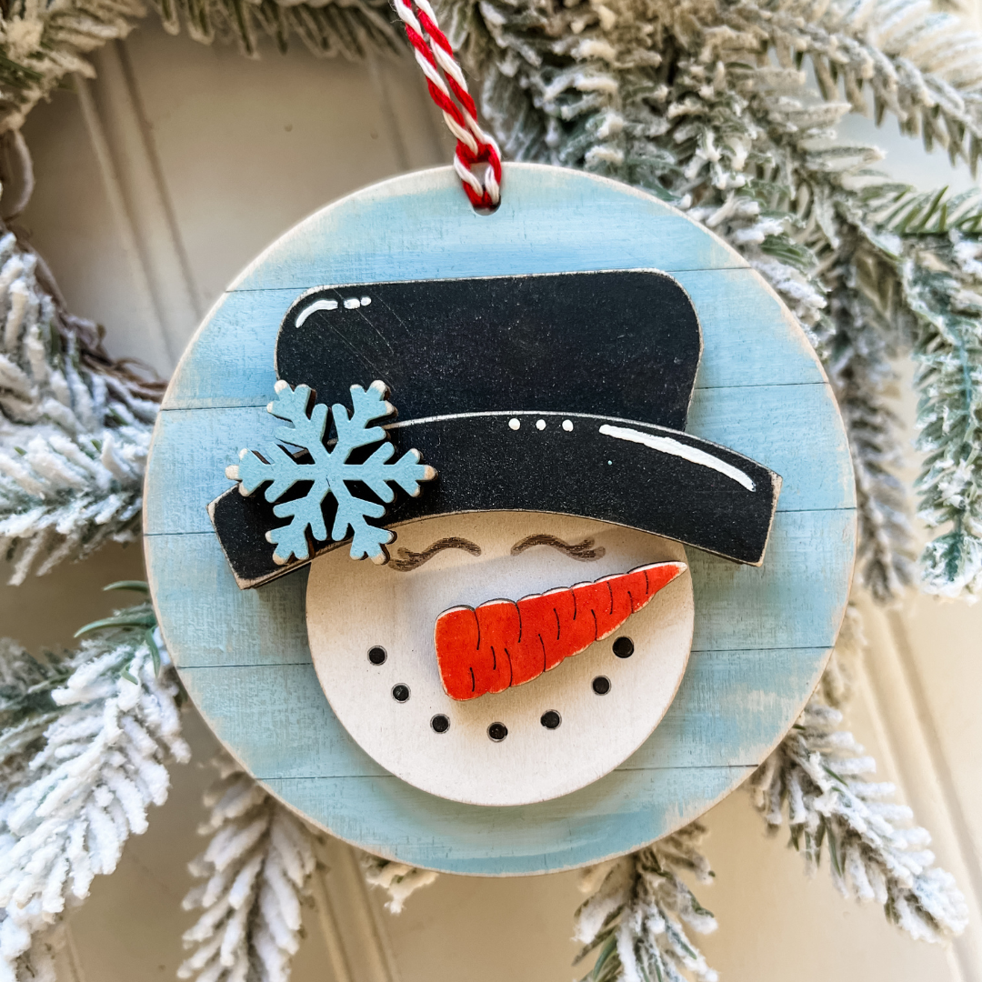DIY snowman Christmas ornament kit with wooden snowman, black top hat, blue snowflake and carrot nose