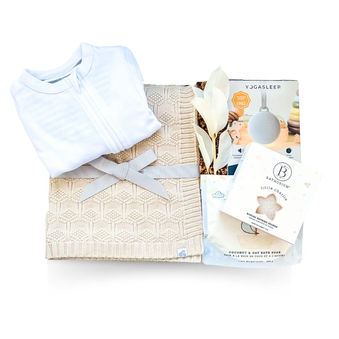 Soft Beginnings luxury baby gift with cream blanket, white onesie, sound machine, and gentle bath items
