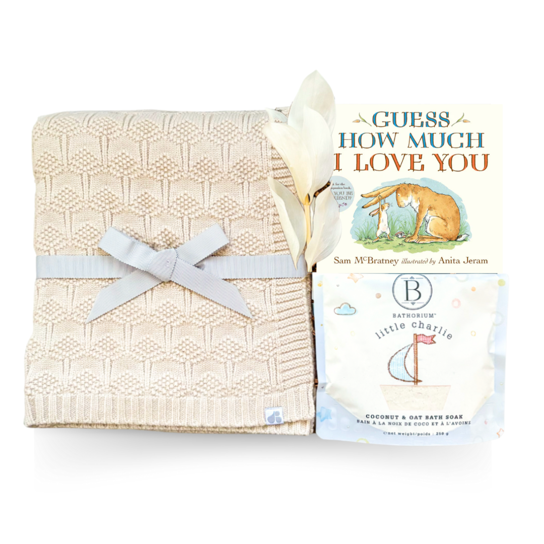Soft Beginnings luxury baby gift with cream blanket, white onesie, sound machine, and gentle bath items
