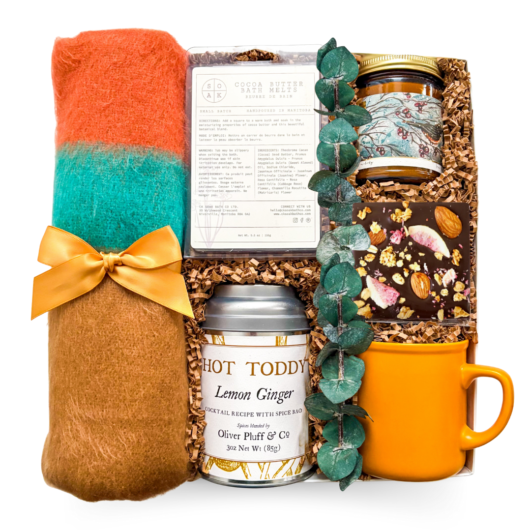 Comforting gift with a blanket, tea, candle, and chocolate, styled for calming and restorative moments.