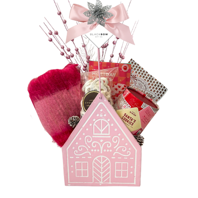 Sugarplum Wishes Christmas gift basket featuring a soft pink scarf, gourmet chocolates, festive sweets and candle in a blush pink gingerbread cottage keepsake.