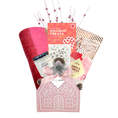 Sugarplum Wishes Christmas gift basket featuring a soft pink scarf, gourmet chocolates, festive sweets and candle in a blush pink gingerbread cottage keepsake.