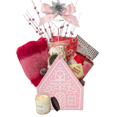 Sugarplum Wishes Christmas gift basket featuring a soft pink scarf, gourmet chocolates, festive sweets and candle in a blush pink gingerbread cottage keepsake.