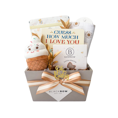 Sunshine & Snuggles neutral baby gift box with Guess How Much I Love You board book, Bathorium Little Charlie baby care, sunshine muslin swaddle, ice cream plush, and premium gift packaging.
