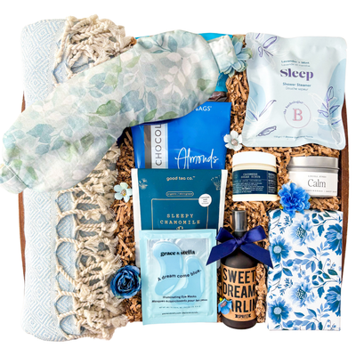 Blue and neutral Sweet Dreams spa gift box featuring Turkish towel, sleep mask, calming self-care products, tea, chocolates, eye masks, and cozy relaxation items in a keepsake wood tray curated by Black Bow Gift Co.
