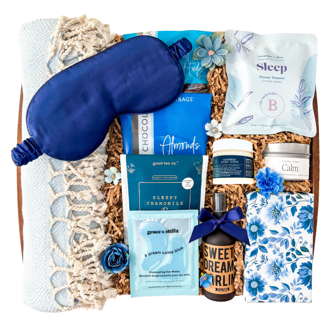 Blue and neutral Sweet Dreams spa gift box featuring Turkish towel, sleep mask, calming self-care products, tea, chocolates, eye masks, and cozy relaxation items in a keepsake wood tray curated by Black Bow Gift Co.