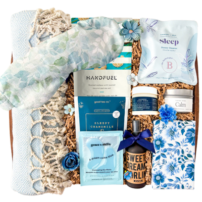 Blue and neutral Sweet Dreams spa gift box featuring Turkish towel, sleep mask, calming self-care products, tea, chocolates, eye masks, and cozy relaxation items in a keepsake wood tray curated by Black Bow Gift Co.