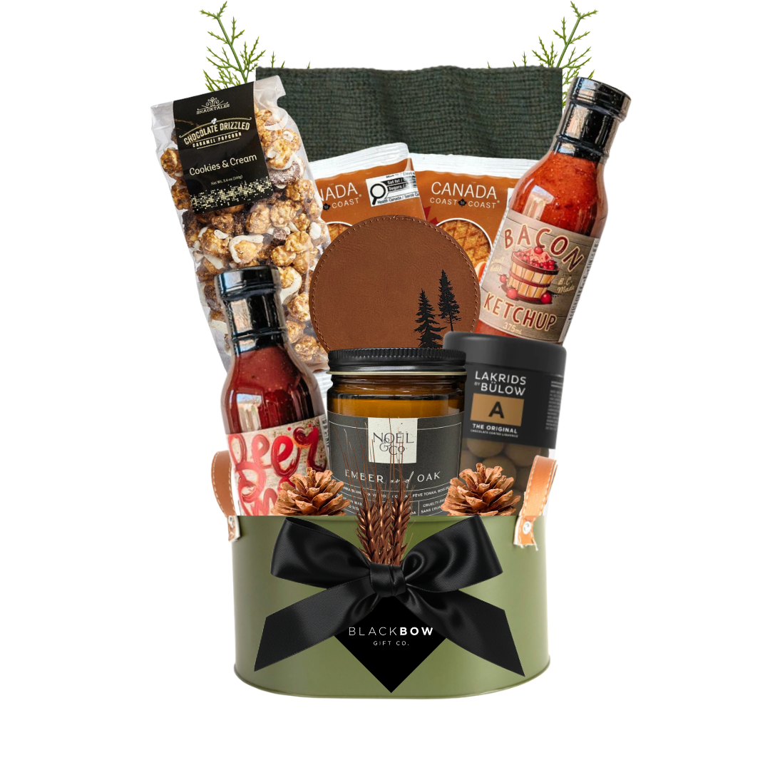 The Lodge Collection luxury gift basket featuring cozy knitwear, gourmet snacks, artisan sauces, a scented candle and leather accessories in an olive green metal keepsake caddy.