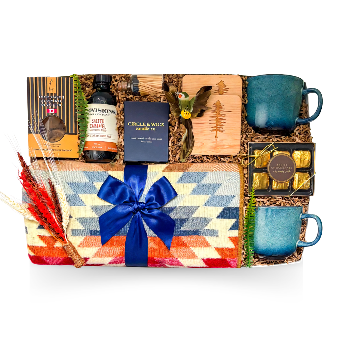 The Perfect Escape luxury gift box featuring a colourful woven throw blanket, two blue ceramic mugs, wooden coasters, candle, gourmet chocolates and treats.